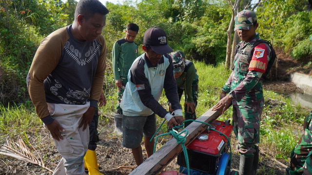 Satgas TMMD Bersama Masyarakat Gotong Royong Memikul Mesin Air untuk Program Manunggal Air